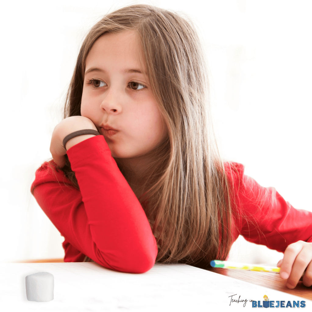 This image shows a young girl with a marshmallow on her desk.
